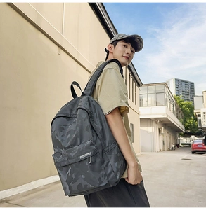Side view of dark gray camouflage waterproof backpack shown on model in urban street setting