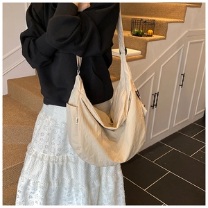 Detail of beige wrinkled nylon dumpling bag showing side pocket and cloth brand label