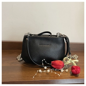 Détail du sac seau en cuir grainé noir avec chaîne argentée et pendentif tulipe