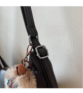 Dettaglio della tracolla regolabile sulla borsa tote marrone con ciondolo a forma di orso