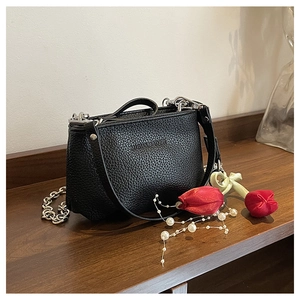 Détail du sac seau noir grainé avec chaîne argentée et bandoulière en cuir souple