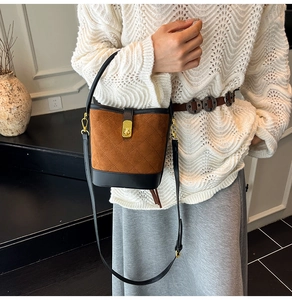 Détail d'un sac seau matelassé en daim marron avec un fermoir doré et bandoulière