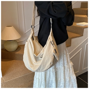 Detail of a large off-white crescent crossbody bag worn over the shoulder by a model
