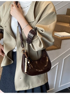 Retro dark brown patent leather crescent bag with wooden bead tassels on stairs