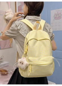 Détail d'un sac à dos à carreaux jaunes avec un joli pendentif agneau en peluche blanche