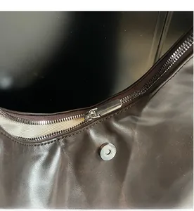 Dettaglio della cerniera argentata e della chiusura magnetica sulla borsa in pelle marrone