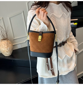 Détail du sac seau matelassé en daim marron avec fermoir doré et accents en cuir noir