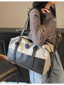 Large beige and black canvas travel bag with adjustable strap and shoulder handles