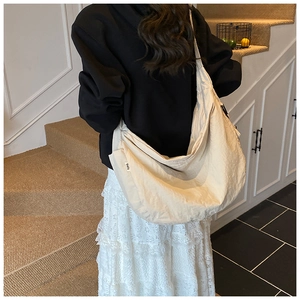 Detailed back view of an ivory crescent dumpling bag showing textured nylon and side logo