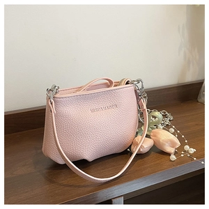 Détail du sac en cuir grainé rose avec chaîne argentée et pendentif décoratif en perles