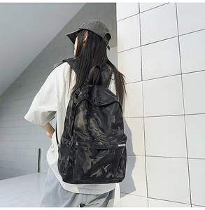 Detailed back view of a camouflage nylon backpack worn by a model in a street style setting