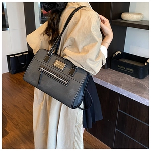 Detail of grey textured fabric and black leather handles on minimalist shoulder tote bag