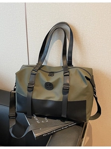 Large olive green nylon travel bag with black leather straps and adjustable shoulder strap