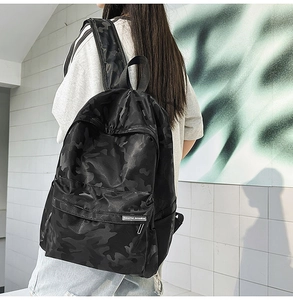 Detail view of black camo backpack showing the textured fabric and front zipper pocket