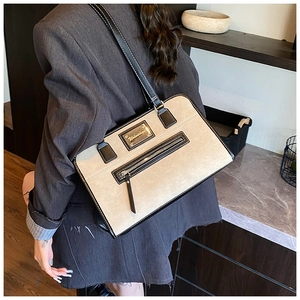 Side view of beige lace tote bag with black leather trim worn by model in store
