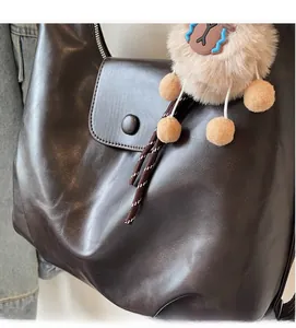 Dettaglio della borsa in pelle marrone con patta e grazioso ciondolo in peluche
