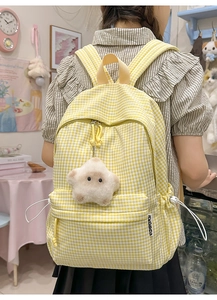 Détail du sac à dos à carreaux jaune et blanc avec breloque étoile et boucle latérale