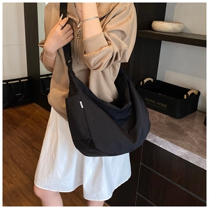 Close-up of black nylon hobo bag with wide shoulder strap worn by a model in interior