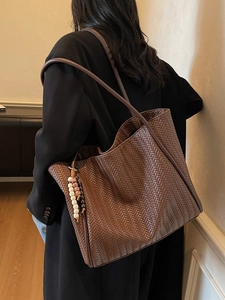 Large dark brown woven leather tote bag for women with decorative tassel detail