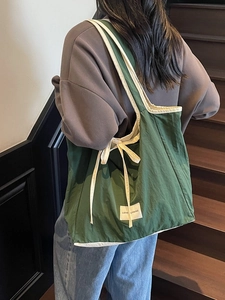 Retro dark green oversized tote bag with cream bow straps and woven label detail