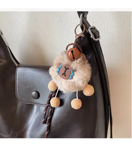 Dettaglio di un ciondolo a forma di pupazzo di peluche con campanello su una borsa di pelle