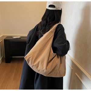 Detail of the light khaki canvas tote bag showing the wide strap and slouchy pleated texture