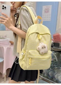 Détail du sac à dos en toile à carreaux jaunes avec peluche étoile dans un style campus