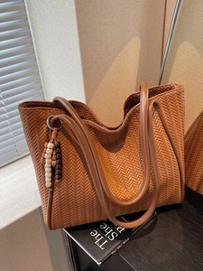 Minimalist dark brown woven tote bag with vintage wooden bead charm for commuting