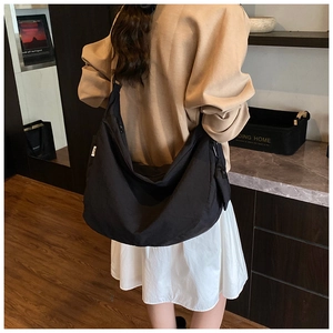 Detail of the large black canvas crossbody bag shown on a model with a wide strap