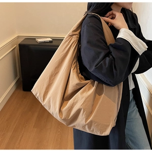 Detailed view of khaki large capacity canvas tote bag worn as a shoulder bag