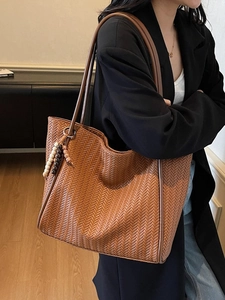 Brown woven tote bag with beaded charm and shoulder strap for casual autumn outfits
