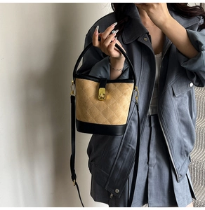 Détail du sac seau en daim matelassé avec garniture en cuir et fermoir rotatif doré