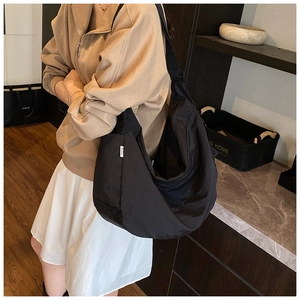 Side view of black large-capacity nylon hobo bag showing its soft curve and wide strap