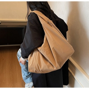 Detail of a large khaki canvas tote bag showing textured fabric and casual slouchy shape
