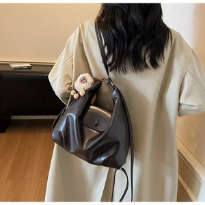 Dettaglio della borsa tote in pelle vintage marrone con pieghe e ciondolo a agnello