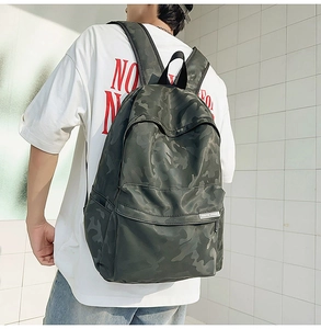 Waterproof camo backpack shown from a side view in a modern outdoor urban setting