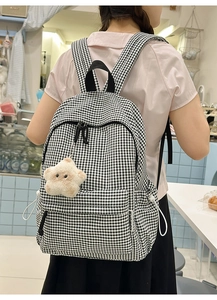 Détail du sac à dos en toile à carreaux noirs et blancs avec pendentif étoile en peluche