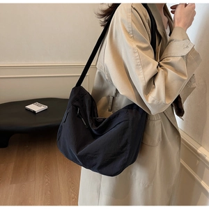 Detailed view of black pleated nylon crescent crossbody bag with adjustable wide strap