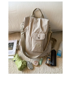 Detail of beige nylon travel backpack with SNAN brand patch and front snap pocket