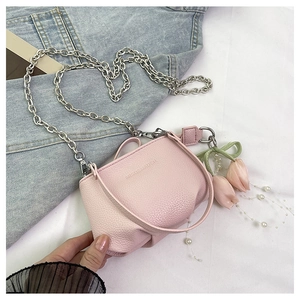 Détail d'un sac seau en cuir rose avec chaîne argentée et breloque tulipe et perle