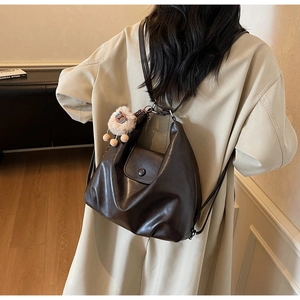 Dettaglio borsa hobo vintage in pelle marrone con patta magnetica e charm in peluche