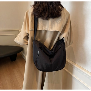 Close-up of black pleated dumpling bag with wide shoulder strap on model's back