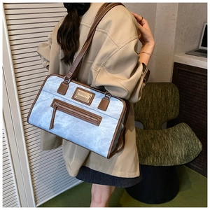 Detail showing marble texture shoulder bag with leather trim and metal plate on a model