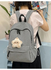 Détail du sac à dos en toile à carreaux noir et blanc avec breloque étoile et étiquette latérale