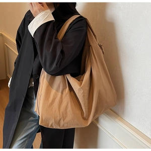 Khaki canvas tote bag shown on model with black coat for a casual slouchy office look