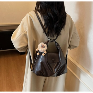 Dettaglio di borsa a spalla in pelle marrone scuro con ciondolo alpaca in peluche bianco