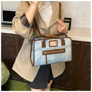 Blue denim tote bag with brown leather trim shown in a professional office setting