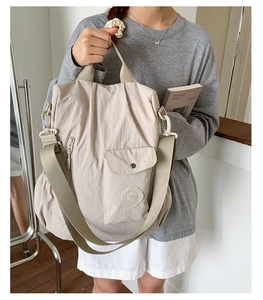Detail of beige nylon crossbody bag with wide strap and multiple utility pockets