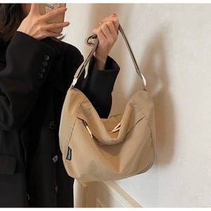 Detail of khaki nylon pleated crossbody bag with woven label and adjustable strap