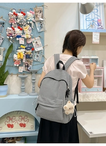 Détail du sac à dos en toile à carreaux avec double fermeture éclair et pendentif étoile
